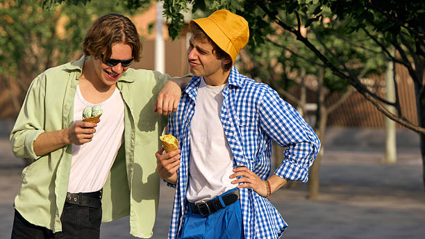 Two friends, gen z, enjoy ice cream outdoors on a sunny day. Concept of friendship and leisure in a vibrant urban setting.