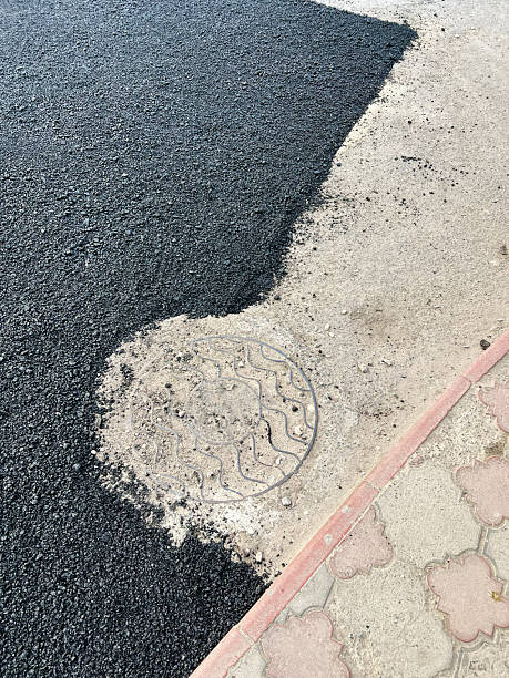 istock Freshly laid asphalt beside a patterned sidewalk showing a manhole cover 2223550233