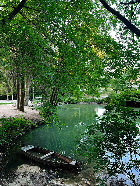 istock Serene riverside scene with a boat docked under lush green tree canopy 2223550350