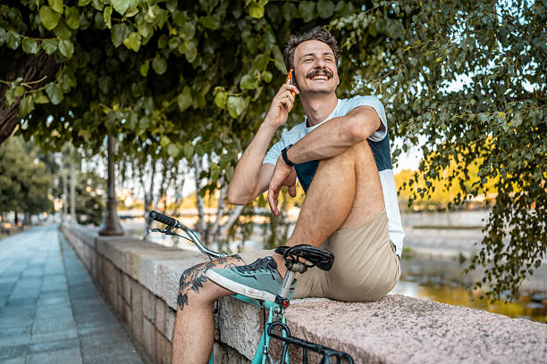 istock Smiling Man Relaxing With His Bicycle While Speaking on a Smartphone 2223551130