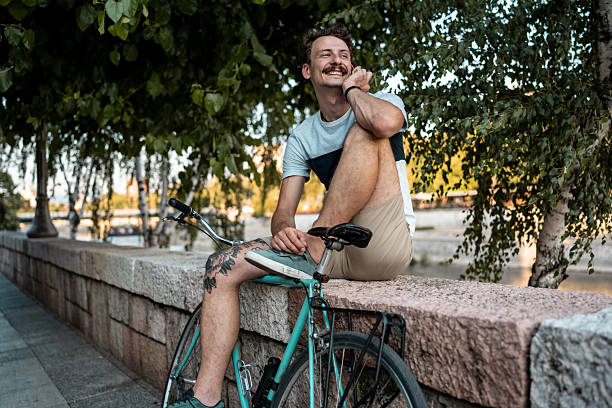 istock Young Man Relaxing Outdoors on a Park Bench with His Bicycle Nearby 2223551136