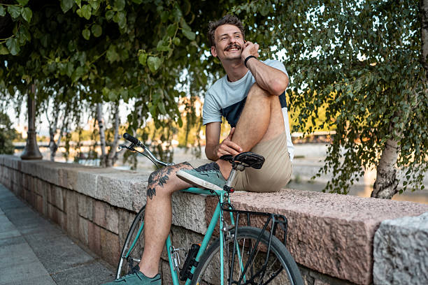 istock Man Sitting on Retaining Wall With Bicycle in Urban Green Area 2223551146