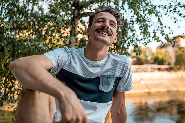 istock Joyful Young Man Smiling in a Relaxed Outdoor Park Setting 2223551160
