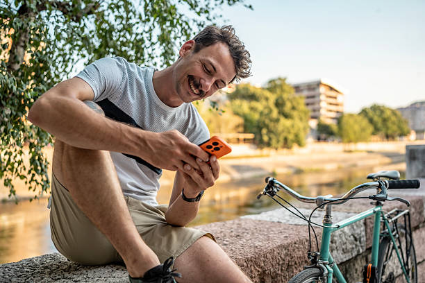 istock Man Relaxing by River While Browsing on Smartphone Near Bicycle 2223551175