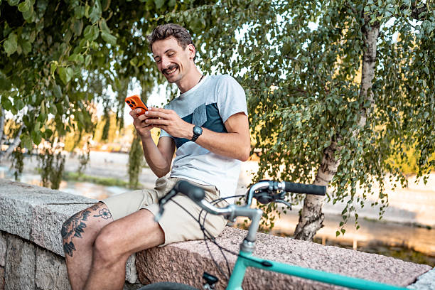 istock Man Relaxing Outdoors with Smoothie and Smartphone Near a Bicycle 2223551210