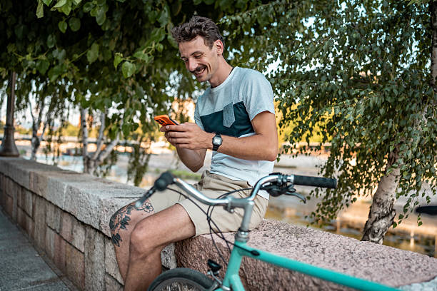 istock Smiling Man Relaxing Outdoors With Phone and Bicycle by Greenery 2223551228