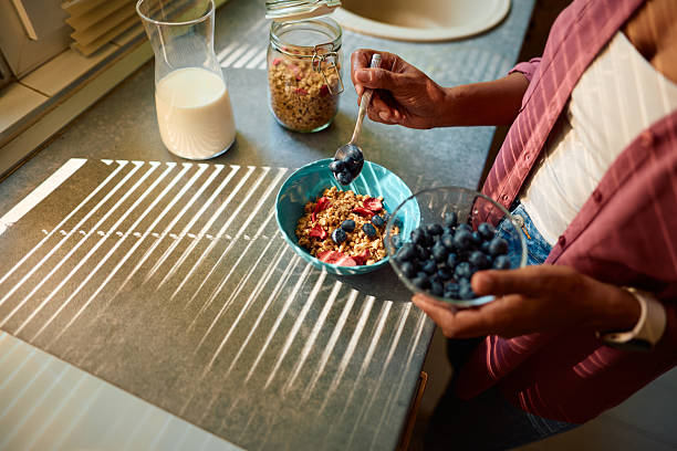 istock Woman adding blueberries to her breakfast muesli in a bowl 2223553871