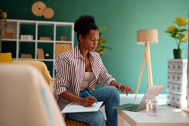 istock Focused young woman working from home using laptop and taking notes 2223554239