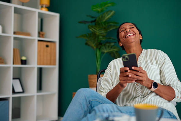 istock Cheerful mid adult woman laughing while using smartphone at home 2223554242