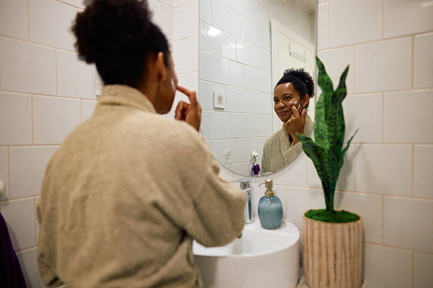 istock Woman applying moisturizer on her face in the bathroom 2223554397