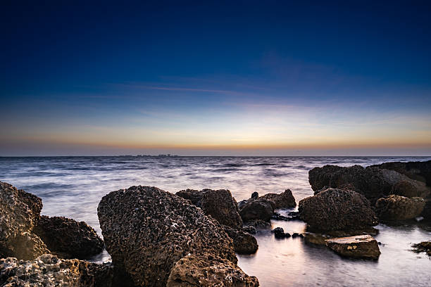 ocean shore with rocks at dusk