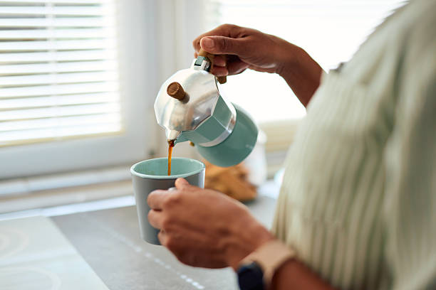 istock Woman pouring coffee from moka pot into mug in kitchen 2223554616