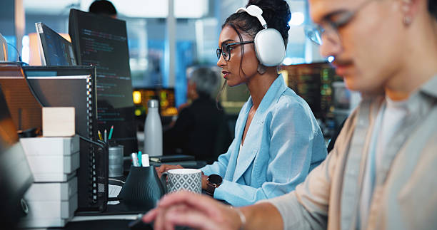 istock Office, businesswoman and headphones with computer for coding, web development and listening to music. Coworking, night and female programmer with digital for programming, software update or podcast 2223559900