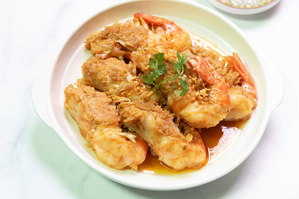 Deliciously fried shrimp served on a white plate, garnished with herbs and complemented by a flavorful sauce.
