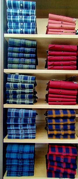 istock Neatly arranged stacks of folded men's shirts in various colors and patterns on display in a retail clothing store 2223567533