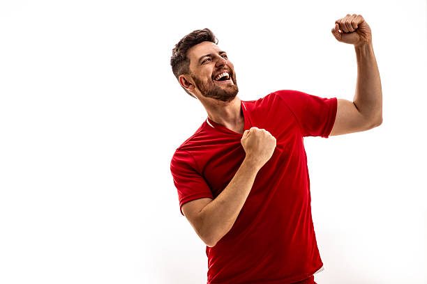 istock Ecstatic soccer fan celebrating victory in red jersey 2223568854
