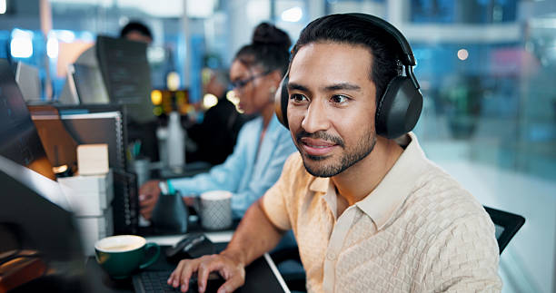 istock Office, businessman and headphones with computer for coding, web development and listening to music. Coworking, night and male programmer with technology for programming, software update and podcast 2223571235