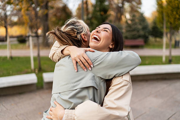 istock Two young women hugging and laughing in a park 2223571618