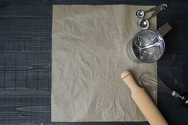 istock Baking utensils arranged on black wooden surface with parchment paper 2223572161