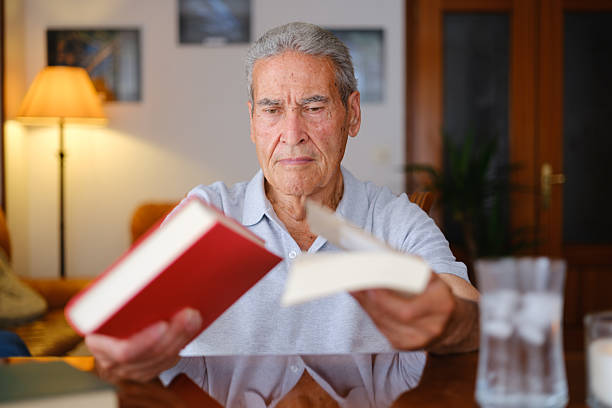 istock Senior man choosing between two books at home 2223572974