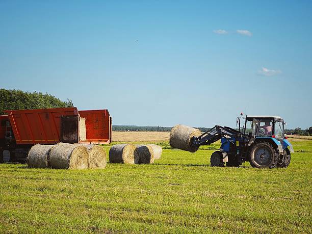 istock tractor loading hay bales in a truck across a vast field on summer day 2223573321