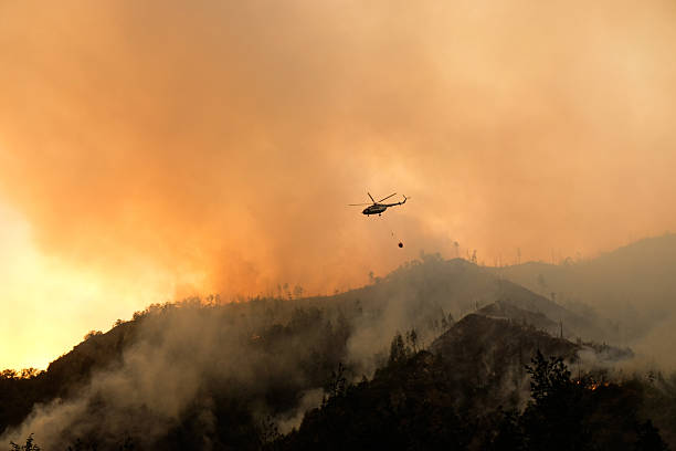 istock Helicopter Drops Water on Wildfire in Mountain Forest 2223573529