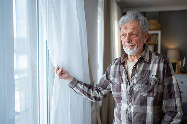 istock Senior man opening curtains and looking out the window 2223577106