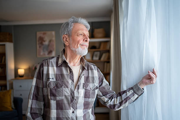 istock Senior man looking out the window in thoughtful contemplation 2223577107