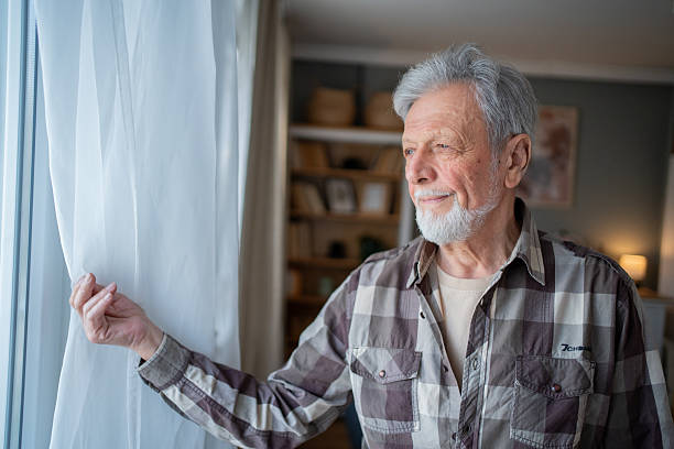 istock Senior man opening curtains and looking out the window 2223577111