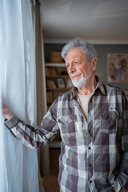 istock Senior man looking out the window with hope 2223577117