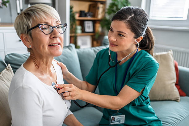 istock Female nurse examining senior woman with stethoscope at home 2223578564