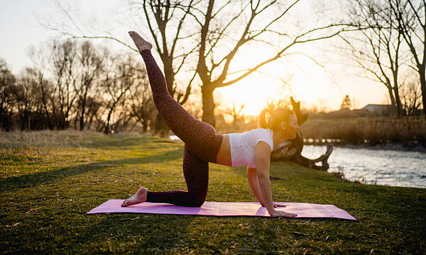 istock Young woman practicing yoga at sunset by the river 2223584709