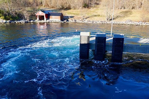 Strong current envelops a concrete pier as a car ferry maneuvers with its powerful side thrusters to depart.