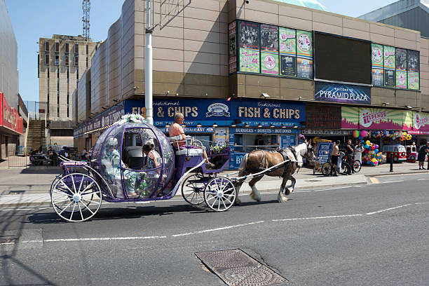 View of a horse drawn carriage in the centre Blackpool, UK.  People can be seen on the carriage and on the promenade
