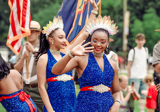 Young African American dancers in blue sequin dresses perform at the Red, White, and Blue To-Do parade in Philadelphia, USA, July 2, 2025, with American flags in the background.