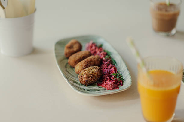 Four golden-brown, crispy chicken croquettes are beautifully arranged on a plate, accompanied by a vibrant beetroot salad and fresh dill