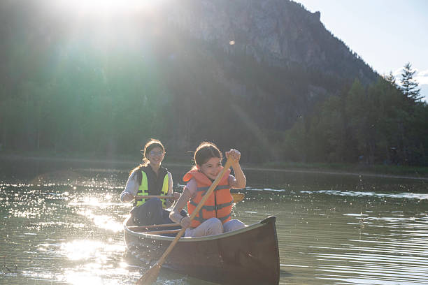 istock Young girls paddle canoe on tranquil lake at sunrise 2223602796
