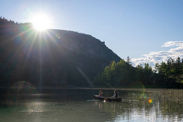 istock Young girls paddle canoe on tranquil lake at sunrise 2223602901