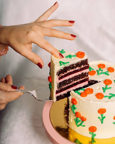 istock Hand lifting a slice of decorated cake 2223608061