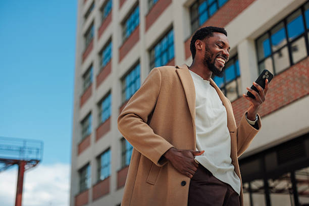 Smiling businessman using smartphone in front of office building