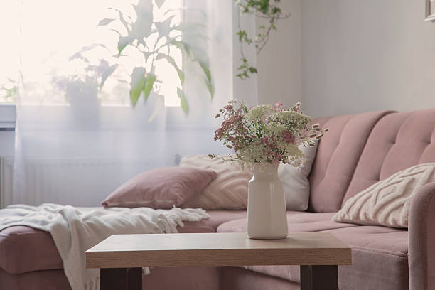 white and pink wilflowers in vase in cozy living room stock photo