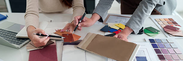 istock Interior Designer Teamwork Asian Women Choosing Color and Material Samples for Home Renovation Project with Fabric, Wood, and Paint Selection 2223614343