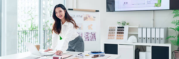 istock Asian Woman Architect at Workstation with Laptop, Sketch, and Material Samples in a Modern Office for Design and Planning Process 2223614477