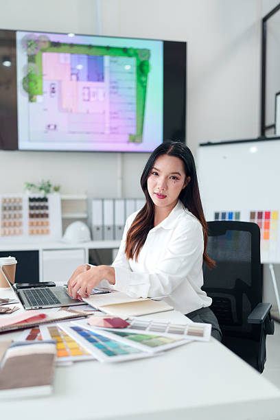 istock Asian Woman Architect at Desk with Laptop and Design Samples in Office Interior Design and Architectural Projects Concept 2223618113