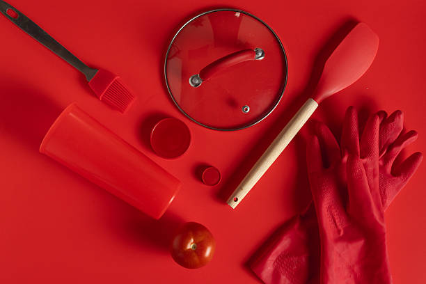 istock Red kitchen utensils, tomato and gloves lying on red background 2223620923