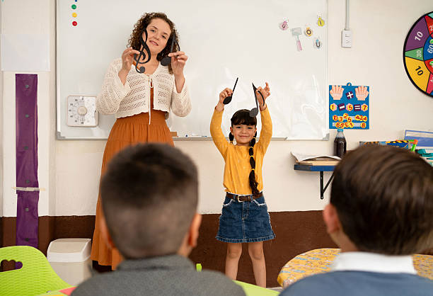 istock Preschool music activity with teacher and student holding musical notes. Fun classroom learning session introducing kids to music symbols and rhythm basics 2223621900