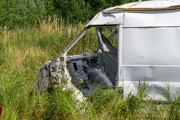istock Abandoned white van body in overgrown grassy field, rusty scrapped delivery vehicle shell 2223632861
