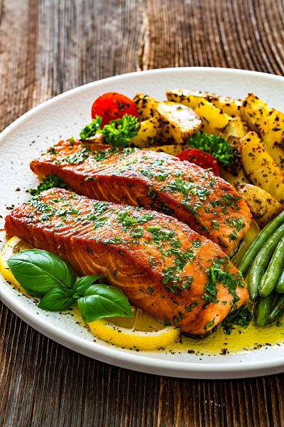 istock Seared salmon steaks with green string beans and roasted potatoes on wooden table 2223645263
