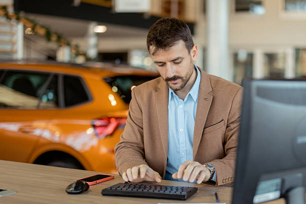 istock Car Dealer at Work in High-End Auto Dealership – Salesman Using Computer in Office Setting 2223652769