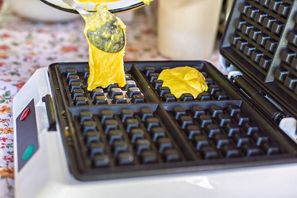 Chef pouring waffle batter into waffle iron